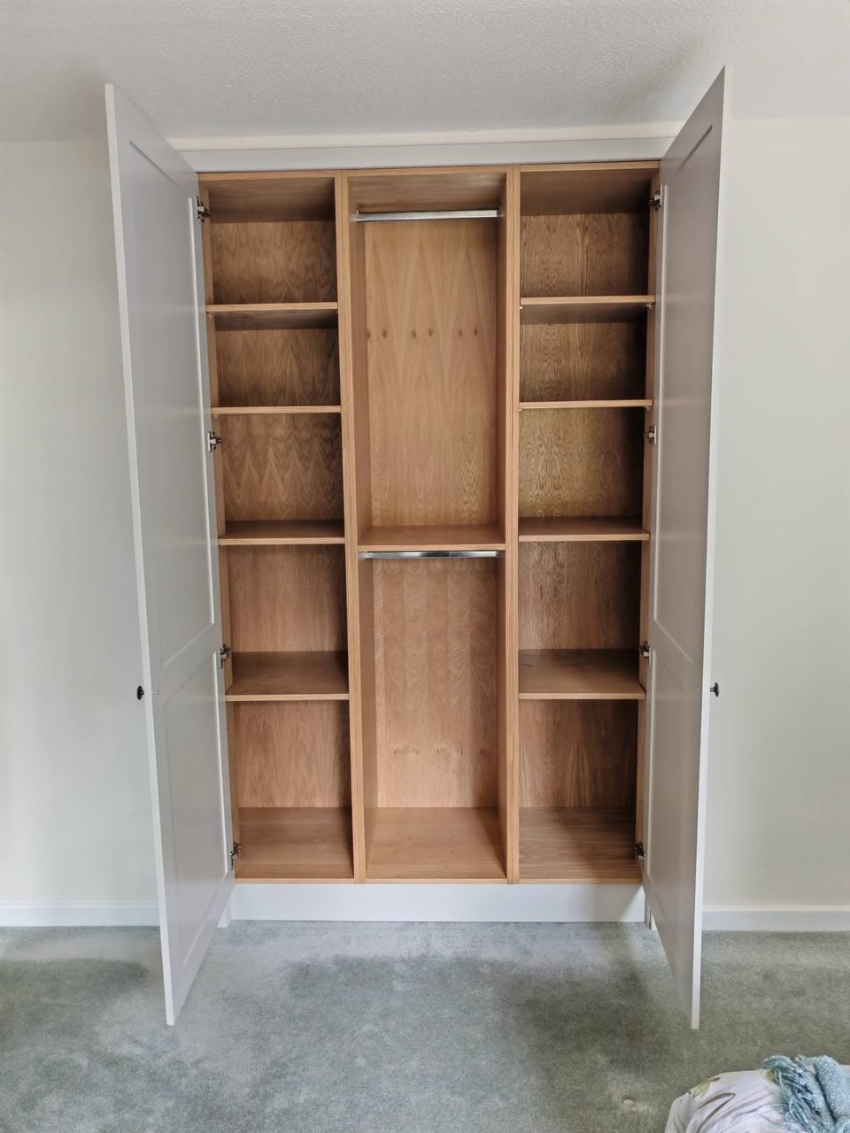 A built-in wardrobe opened to show oak-lined shelving and hanging space