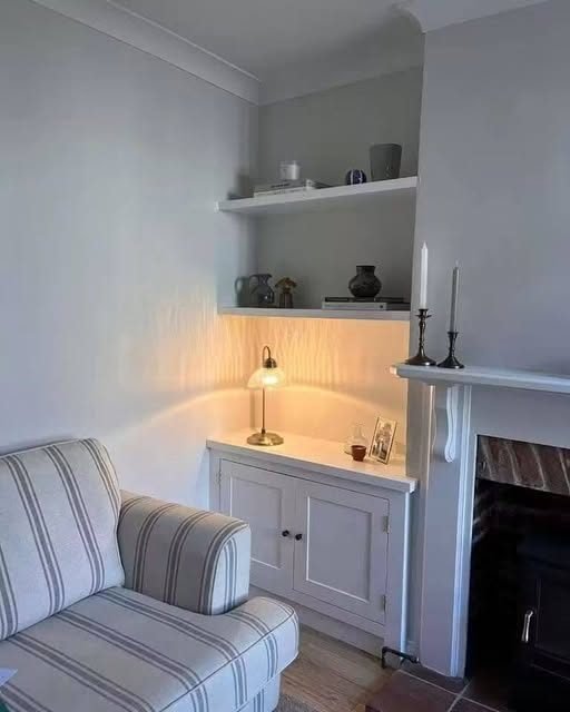Alcove cabinetry with lit display shelving beside a fireplace
